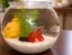 red betta fish in glass bowl with plant and white gravel on table