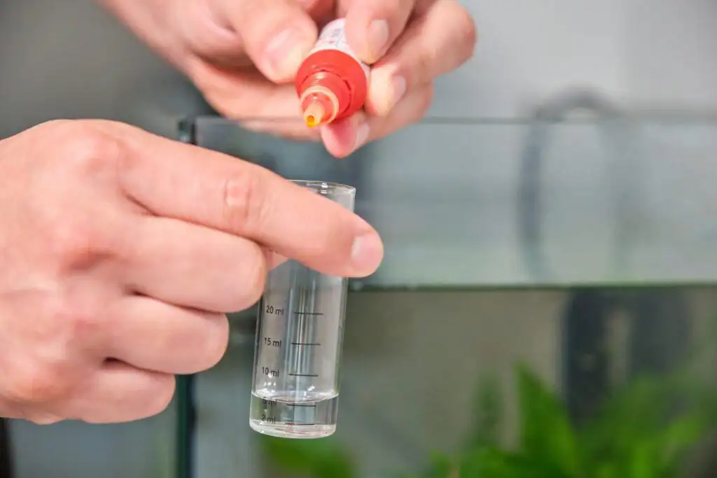 a bettakeeper adding water conditioner in his betta tank